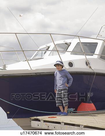 Picture - Boy standing by a boat. Fotosearch