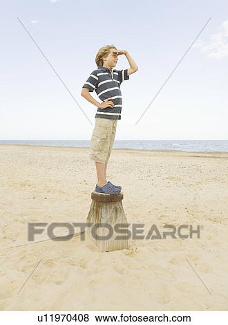 Stock Photo - Boy standing on groyne. Fotosearch
