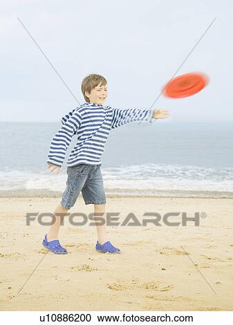 Stock Image - Boy throwing Frisbee on beach. Fotosearch