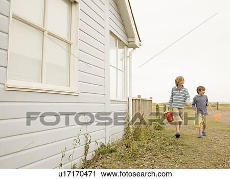 Stock Image - Boys walking past house. Fotosearch