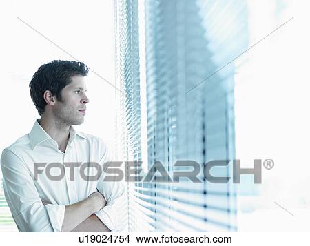 Picture - Business man looking through window. Fotosearch