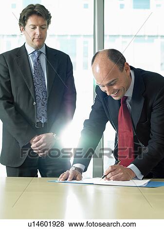 Stock Photo - Business man signing papers with partner. Fotosearch