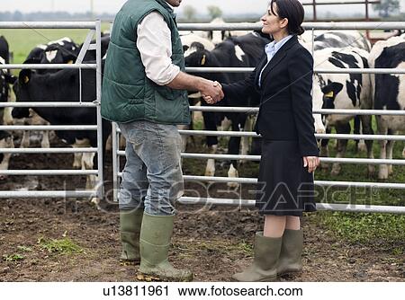 Stock Image - business woman shaking hands with farmer. Fotosearch
