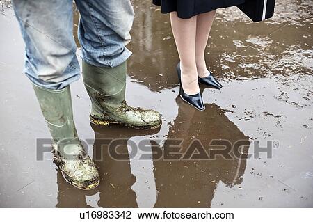 Stock Image - business woman with farmer in mud. Fotosearch