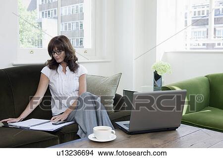 Picture - Business women looking at papers on sofa. Fotosearch