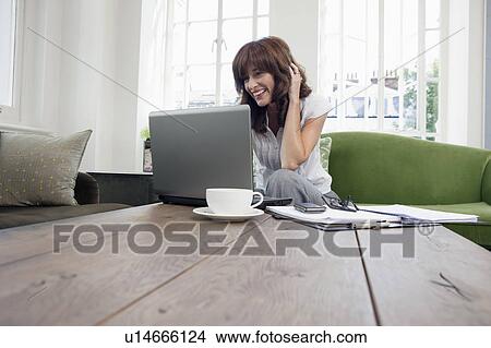 Picture - Business women working on laptop on sofa. Fotosearch