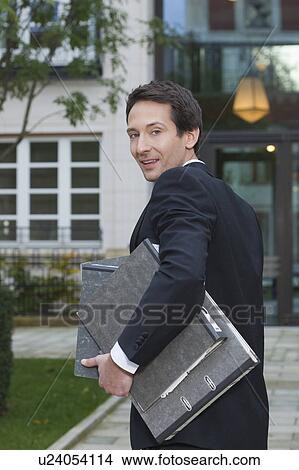 Picture - businessman carrying files, outside. Fotosearch