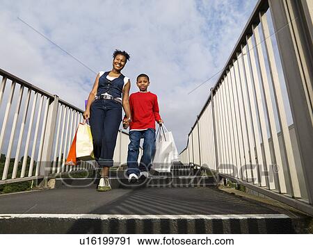 Stock Image - child carrying shopping with mother. Fotosearch