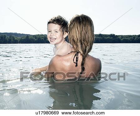 Stock Photo - child laughing over mother's shoulder. Fotosearch
