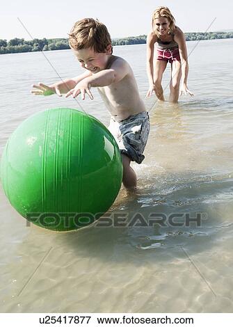 Stock Photo - child with ball in river. Fotosearch
