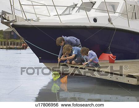 Children fishing by a boat View Large Photo Image Stock Photograph - Children fishing by a boat. Fotosearch