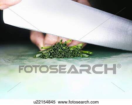 Stock Photography - Close up of a knife cutting chives. Fotosearch