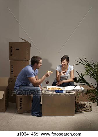 Stock Photography - Couple eating pizza on cardboard box. Fotosearch