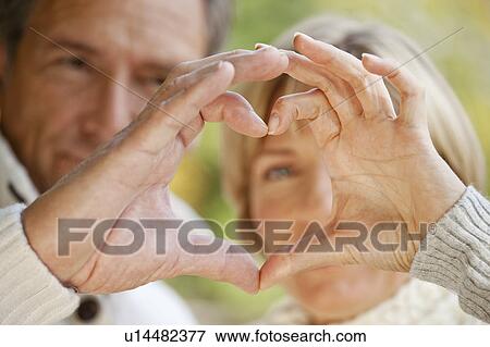 Stock Photo - Couple forming heart with their fingers. Fotosearch