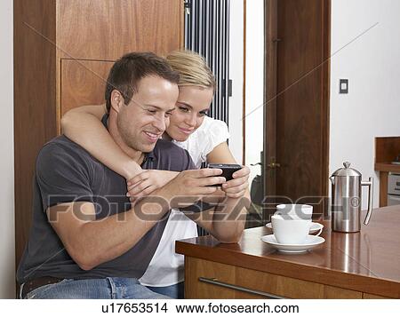 Couple having coffee looking at phone View Large Photo Image Picture - Couple having coffee looking at phone. Fotosearch