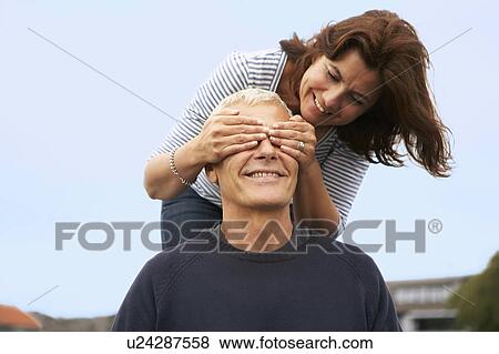 Couple, her hands over his eyes View Large Photo Image Stock Photo - Couple, her hands over his eyes. Fotosearch