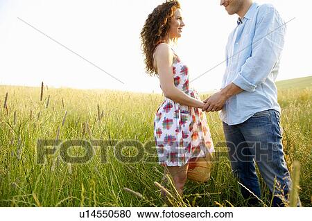 Stock Image - Couple holding hands in a wheat field. Fotosearch