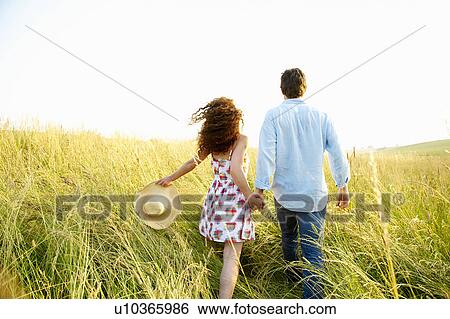 Couple holding hands in a wheat field View Large Photo Image Stock Photograph - Couple holding hands in a wheat field. Fotosearch