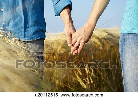 Stock Photography - Couple holding hands in a wheat field. Fotosearch