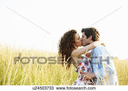 Stock Image - Couple kissing in a wheat field. Fotosearch