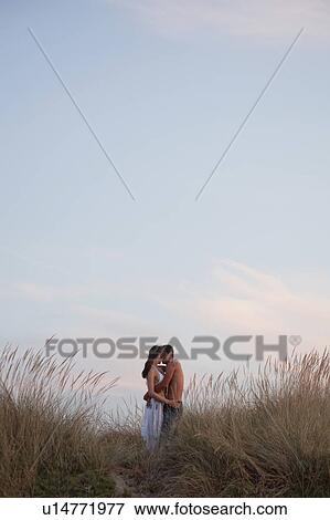 Stock Photo - couple kissing in the reed at the beach. Fotosearch
