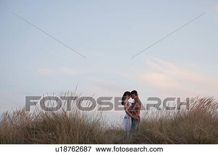 Stock Photo - couple kissing in the reed at the beach. Fotosearch