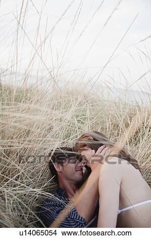 Picture - couple lying in reed embracing. Fotosearch
