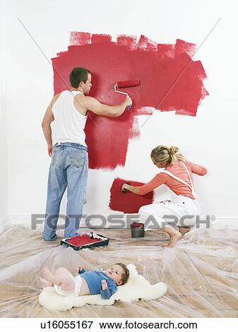 Couple painting a wall, baby on floor View Large Photo Image Stock Photo - Couple painting a wall, baby on floor. Fotosearch