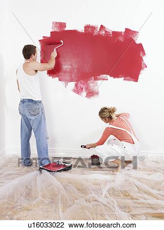 Stock Image - Couple painting a wall. Fotosearch
