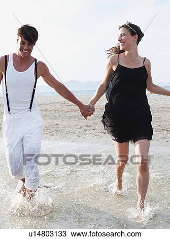Stock Image - couple running on the beach. Fotosearch