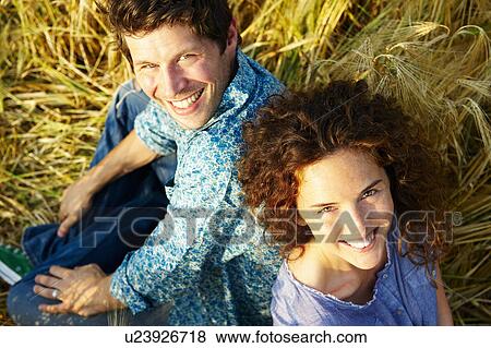 Couple sitting in a wheat field, smiling View Large Photo Image Stock Photo - Couple sitting in a wheat field, smiling. Fotosearch