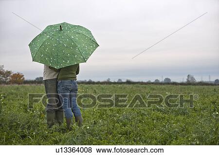 Stock Photo - couple under umbrella in field. Fotosearch