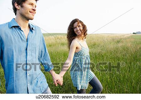 Stock Image - Couple walking in a wheat field. Fotosearch