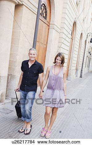 couple with trolly walking along street View Large Photo Image Picture - couple with trolly walking along street. Fotosearch