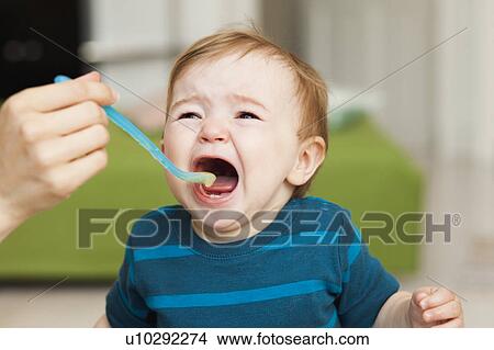 crying baby sitting in chair being fed View Large Photo Image Picture - crying baby sitting in chair being fed. Fotosearch
