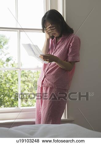 Stock Photo - Distressed Woman with letter by window. Fotosearch
