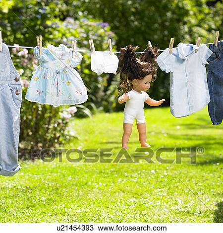 Stock Image - Doll and its clothing on a clothesline. Fotosearch