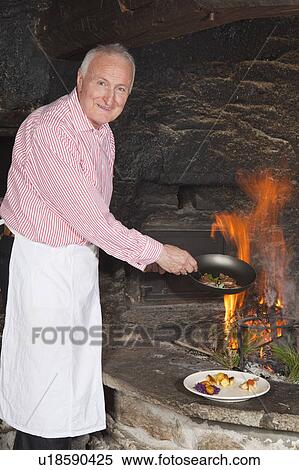 elderly cook by fireplace serving food View Large Photo Image Stock Photography - elderly cook by fireplace serving food. Fotosearch