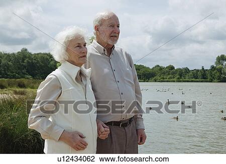 Stock Image - Elderly man holding elderly woman's hand. Fotosearch