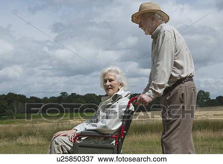 Elderly man pushing woman in wheelchair View Large Photo Image Stock Photo - Elderly man pushing woman in wheelchair. Fotosearch