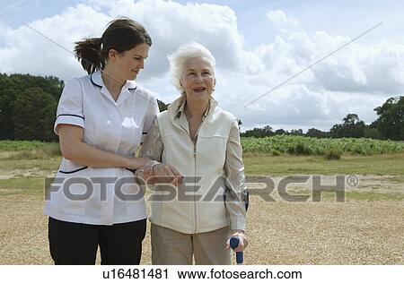 Stock Image - Elderly woman being supported by nurse. Fotosearch