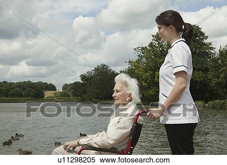 Stock Photography - Elderly woman in wheelchair with nurse. Fotosearch