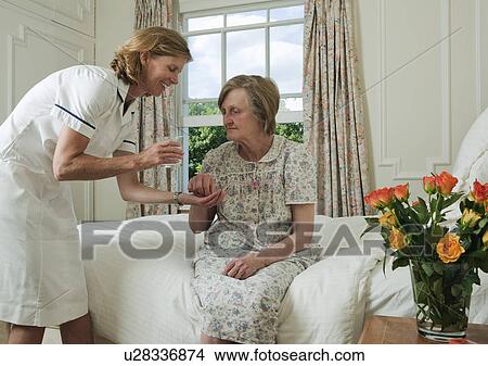 Elderly woman taking pill from nurse View Large Photo Image Picture - Elderly woman taking pill from nurse. Fotosearch