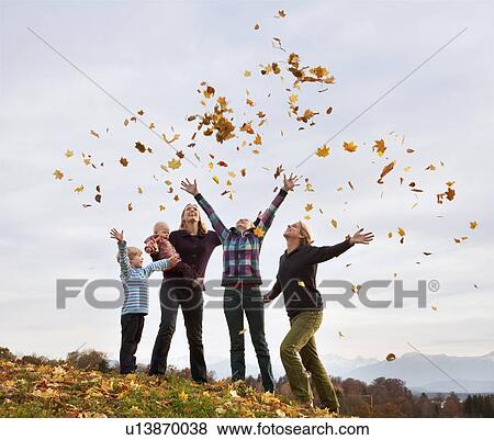 Stock Photo - family throwing autumn leaves into air. Fotosearch