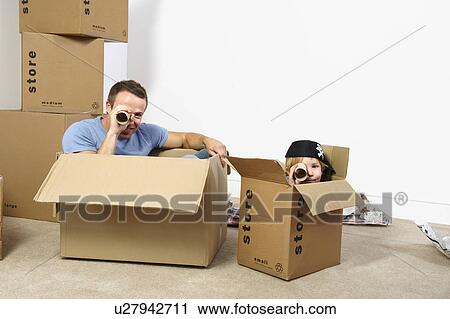 Stock Image - Father and son playing with moving boxes. Fotosearch