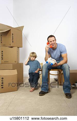 Stock Image - Father and son playing with phones. Fotosearch