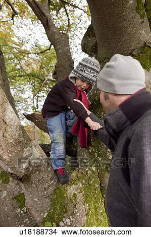 Picture - Father helping son while climbing a tree. Fotosearch