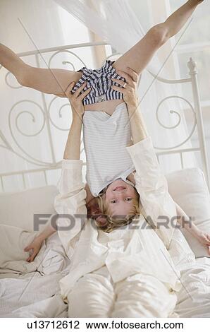 Father holding son upside down in bed View Large Photo Image Stock Image - Father holding son upside down in bed. Fotosearch