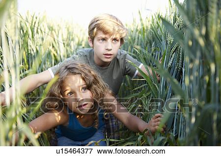 Stock Photo - Girl and boy hiding in a wheat field. Fotosearch