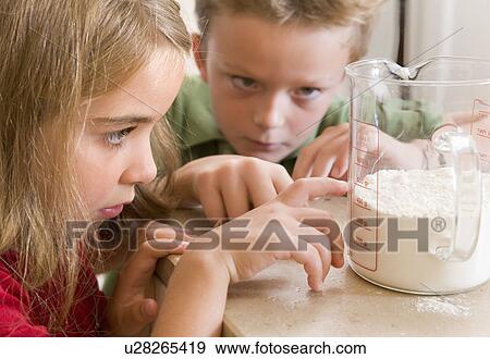 Stock Photo - girl and boy measuring flour. Fotosearch